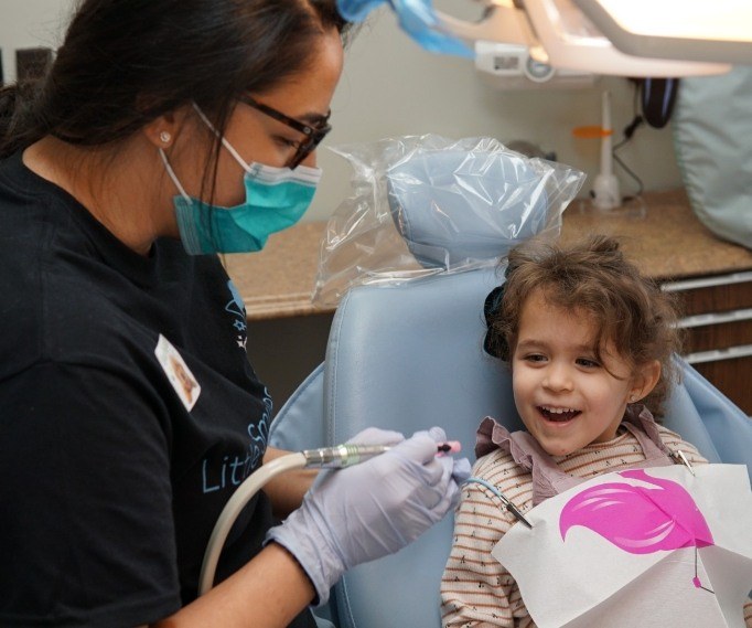 Child in dental chair smiling with dental team member