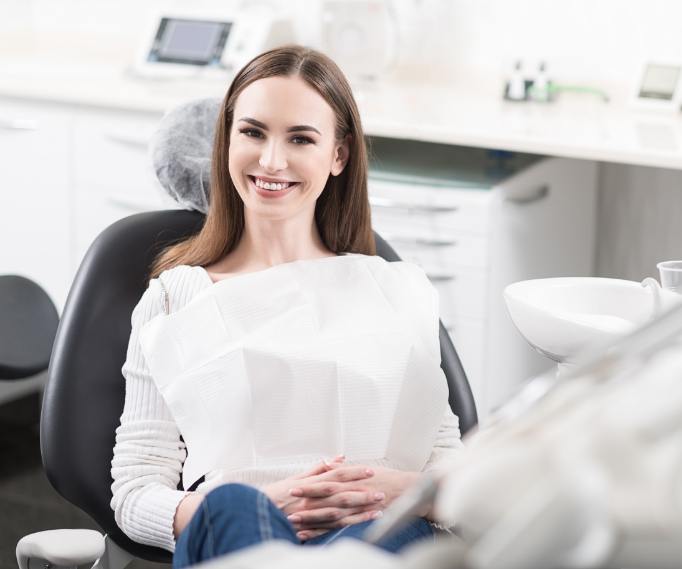 Smiling woman in white sweater sitting in dental chair