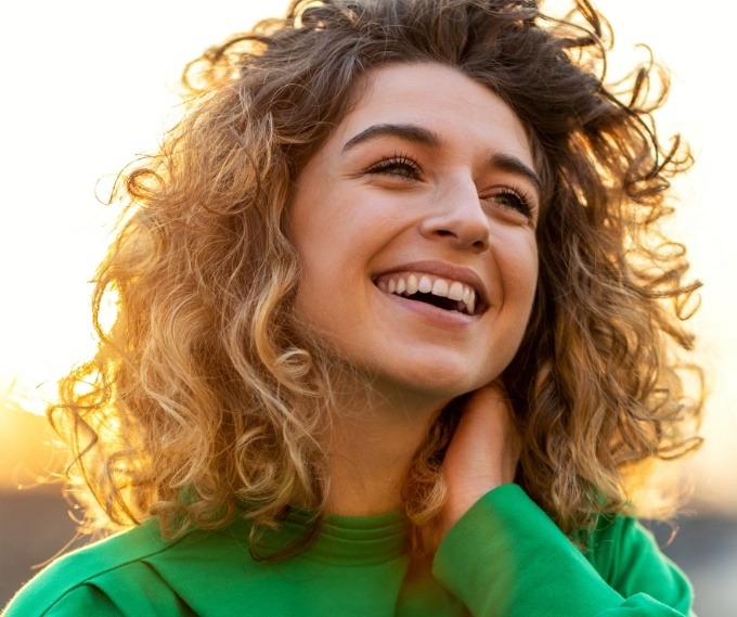 Woman in green sweater smiling outdoors
