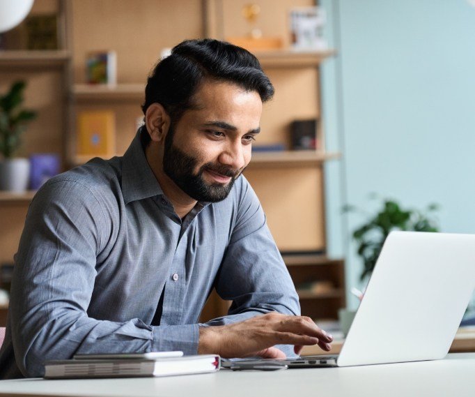 Man sitting at desk and looking at laptop