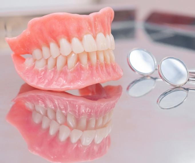 Full dentures on tray next to two dental mirrors